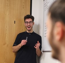 Tumelo team member Harry stands giving an enthusiastic presentation during a whiteboard session.